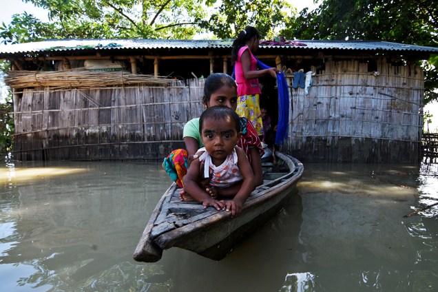 Famílias usam canoas para migrarem para lugares que não foram atingidos pelas enchentes, causadas por fortes tempestades na região de Assam, na Índia - 14/07/2017