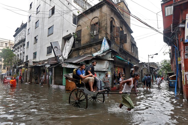 Carroceiro transporta passageiros em sua charrete durante enchente que inundou o centro de Calcutá, na Índia - 07/07/2017