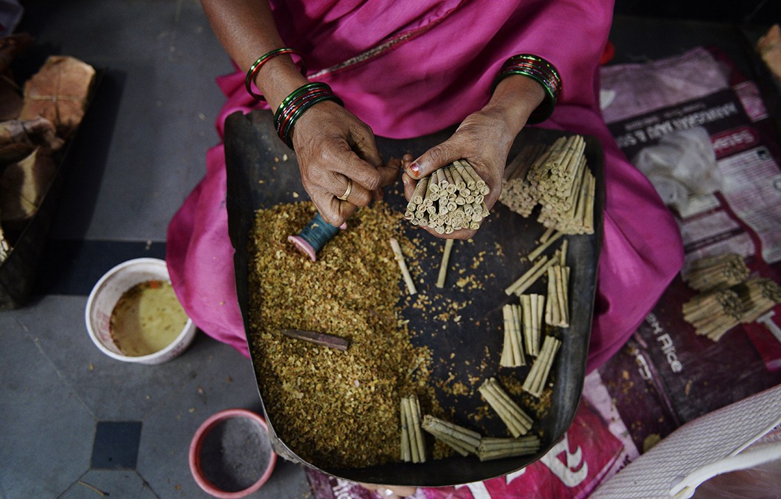 Trabalhadora manipula tabaco e produz cigarros em uma feira na cidade de Nizamabad, na Índia