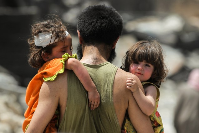 Homem carrega seus filhos nos braços, enquanto foge da Cidade Velha de Mosul durante combate entre as forças do governo iraquiano contra combatentes do Estado Islâmico - 03/07/2017