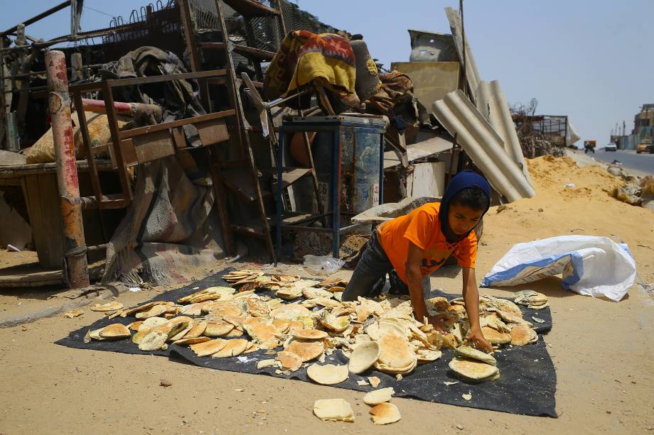 Garoto refugiado espalha pão no chão em um acampamento em al-Shatee, em Gaza - 12/07/2017