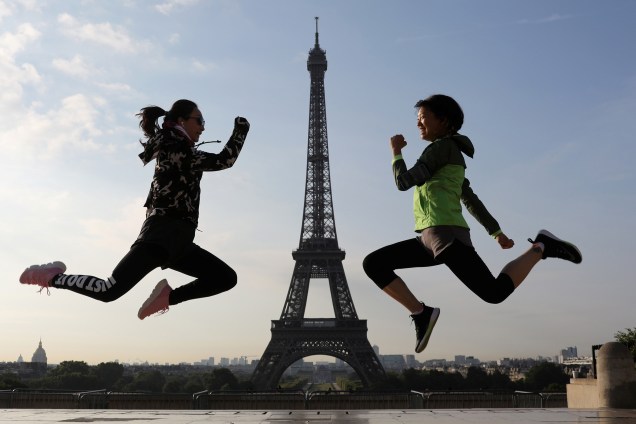 Mulheres saltam para fotografia em frente à Torre Eiffel no Palais de Chaillot, em Paris - 26/07/2017