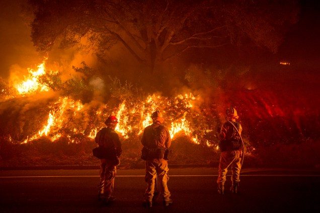 Três homens do corpo de bombeiros da Califórnia lutam contra as chamas do incêndio Detwiler que atingiu a pequena cidade de Mariposa e obrigou centenas de moradores a deixarem suas casas