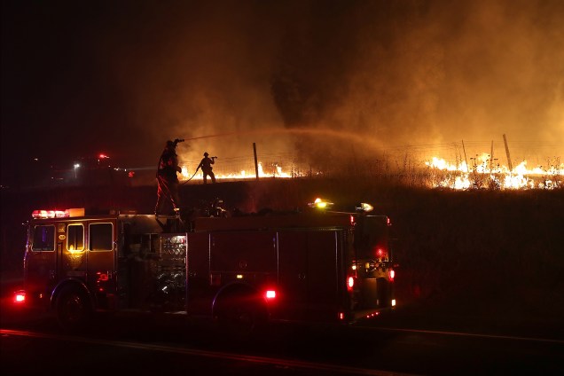 Bombeiros jogam água para conter o incêndio Detwiler em Mariposa, Califórnia. Mais de 1.400 bombeiros estão lutando contra o fogo que queimou mais de 25 mil hectares e forçou centenas de pessoas a evacuar suas casas