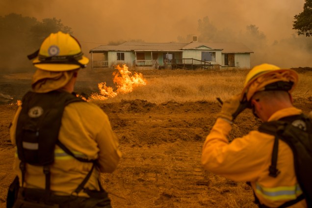 Bombeiros assistem às chamas do incêndio Detwiler, em Mariposa, que cercam uma casa na Califórnia