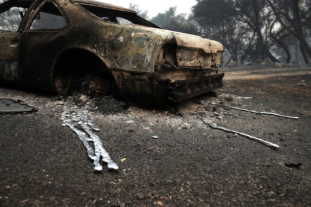 Um carro queimado é fotografo ao lado de uma casa destruída pela incêndio Detwiler que tomou conta de 25 mil hectares em Mariposa, na Carlifórnia