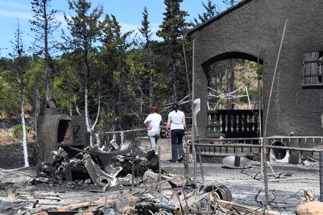 Duas mulheres inspecionam o estrago causado pelo fogo que atingiu sua casa, em Bormes-les-Mimosas, sudeste da França. Cerca de 10 mil pessoas foram obrigadas a deixar suas residências
