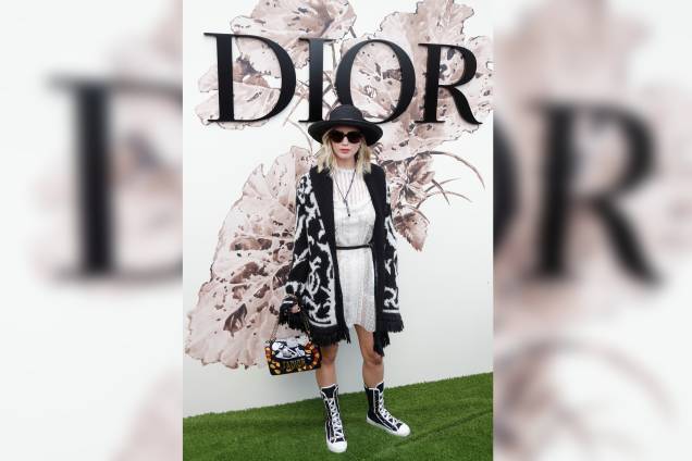 Em um momento pré-glamour, Jennifer Lawrence chegou ao desfile da Dior com tênis de cano alto, chapéu e um vestido branco coberto por um casaco estampado.