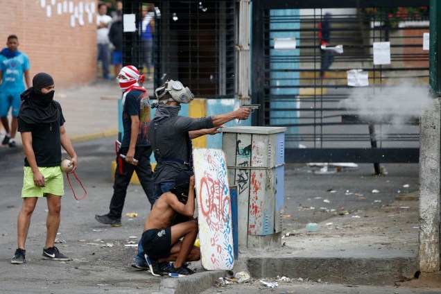 Manifestante dispara uma arma de fogo durante os confrontos com  forças governamentais enquanto se realizam as eleições da Assembleia Constituinte em Caracas, na Venezuela - 30/07/2017