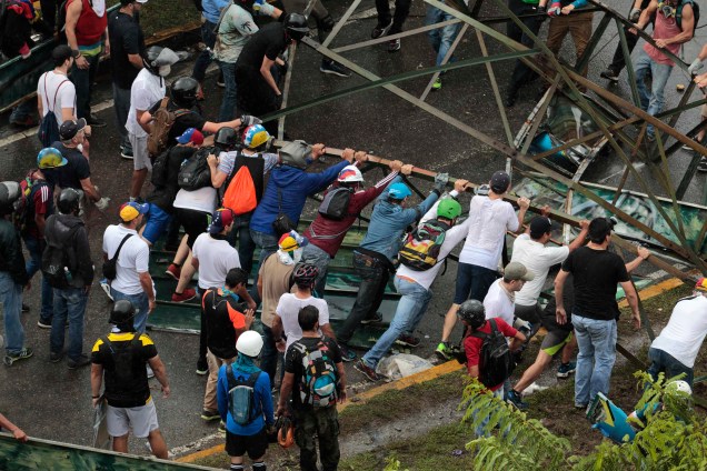 Manifestantes de oposição arrastam uma estrutura metálica para montar uma barricada durante confronto com a polícia em Caracas, na Venezuela - 30/07/2017