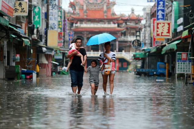 Família caminha em meio a uma rua inundada durante tempestades provocadas pelo tufão Nesat em Pingtung, no sul de Taiwan - 29/07/2017 Família caminha em meio a uma rua inundada durante tempestades provocadas pelo tufão Nesat em Pingtung, no sul de Taiwan - 29/07/2017