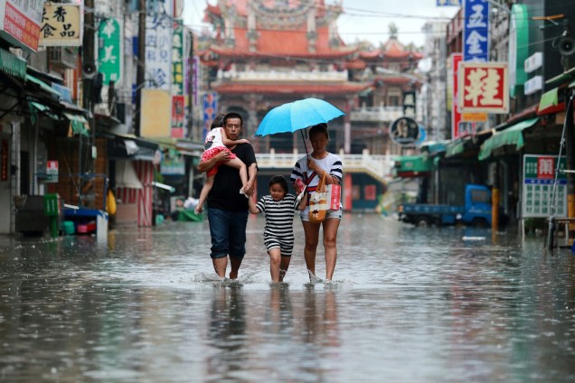 Família caminha em meio a uma rua inundada durante tempestades provocadas pelo tufão Nesat em Pingtung, no sul de Taiwan - 29/07/2017