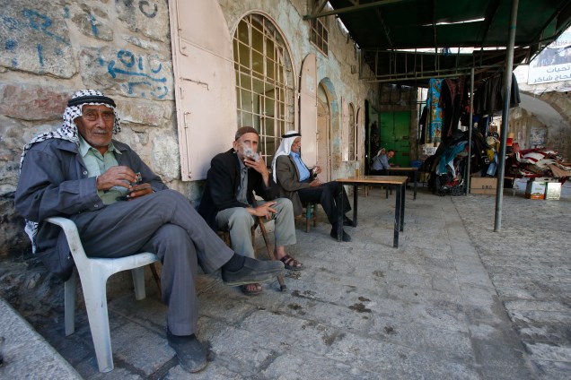 Palestinos idosos fumam cigarros em um café na cidade velha de Hebron, na Cisjordânia