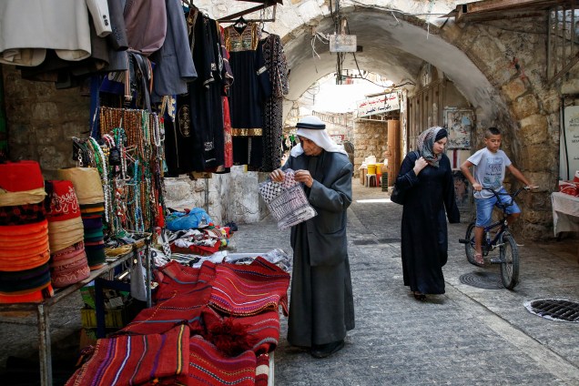 Palestinos transitam em beco no antigo mercado da cidade de Hebron, na Cisjordânia