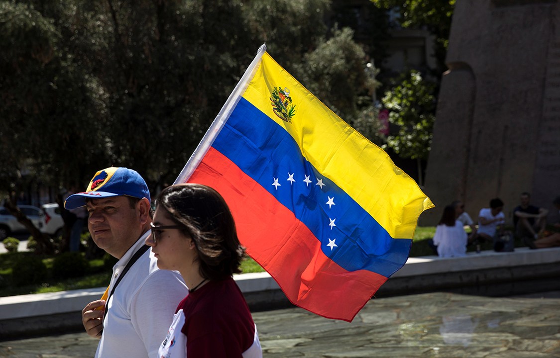 Casal caminha com bandeira da Venezuela como forma de protesto contra o presidente Nicolás Maduro