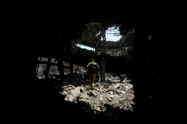 Membros da Divisão Especial de Emergência iraquiana andam sobre escombros de um prédio na Cidade Velha de Mossul, Iraque