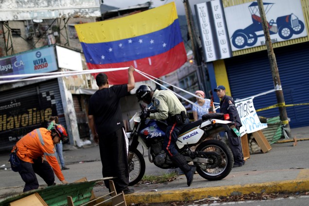 Policial atravessa o bloqueio de uma rua em Caracas com sua motocicleta no primeiro dia de greve convocada por opositores do governo de Nicolás Maduro, na Venezuela - 26/07/2017