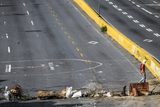 Manifestante da oposição venezuelana anda pela estrada Prado del Este, bloqueada durante a greve geral de 48 horas contra o presidente Nicolás Maduro - 27/07/2017
