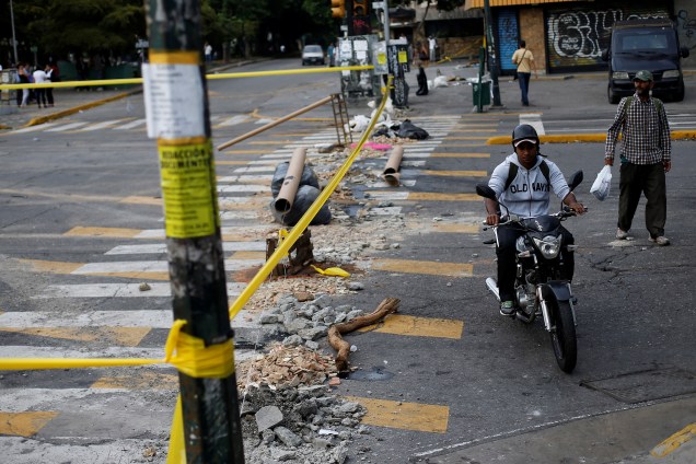 Motociclista passa em frente a uma rua bloqueada durante o segundo dia da greve de 48 horas organizada pela oposição venezuelana contra o presidente Nicolás Maduro, em Caracas - 27/07/2017