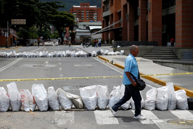 Pedestre caminha em frente a uma rua bloqueada durante o segundo dia da greve geral em Caracas contra o presidente venezuelano Nicolás Maduro - 27/07/2017