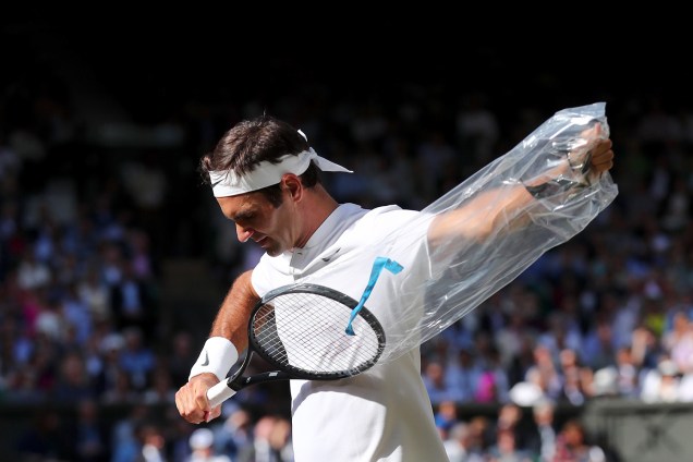 O suiço Roger Federer desempacota uma raquete nova, durante semifinal contra Tomas Berdych, da República Tcheca, em Wimbledon