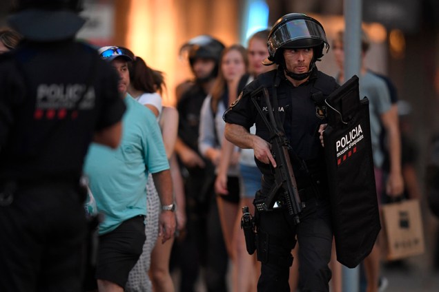 Policiais acompanham clientes de uma loja para fora da área isolada após atropelamento em La Rambla, em Barcelona