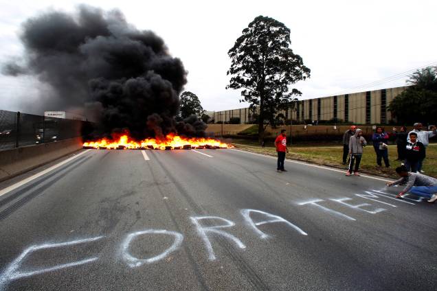 Durante protesto contra Michel Temer na BR116, em São Paulo, membro do MTST pixa o asfalto pedindo a saída do presidente - 02/08/2017