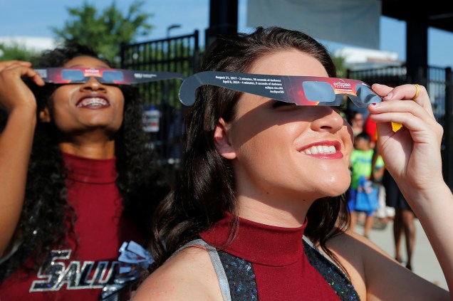 Animadoras de torcida usam óculos de visão solar antes de receber o público em um estádio de futebol-americano para assistir o eclipse solar total na Southern Illinois University em Carbondale, nos Estados Unidos - 21/08/2017