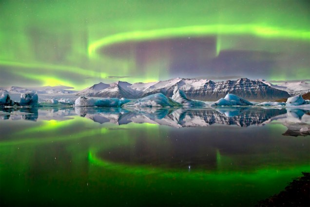 O fotógrafo James Woodend registrou a simetria e as exuberância das cores durante uma aurora boreal em um lago congelado, na geleira de Vatnajökull, Islândia