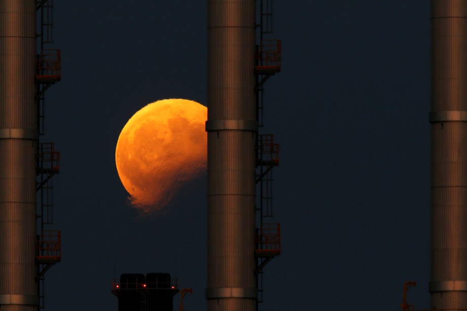 O nascer da lua é fotografado durante o eclipse parcial atrás das chaminés de uma estação de energia elétrica em Delimara, fora da aldeia de Marsaxlokk, em Malta - 07/08/2017