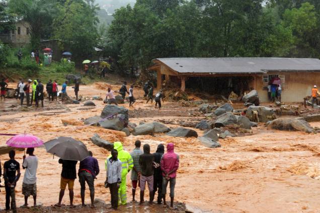 Pessoas observam a lama de um deslizamento de terra que atingiu a capital da África Ocidental, Serra Leoa. Pelo menos 312 pessoas foram mortas e mais de 2.000 perderam suas casas quando as grandes inundações atingiram a cidade de Freetown - 14/08/2017