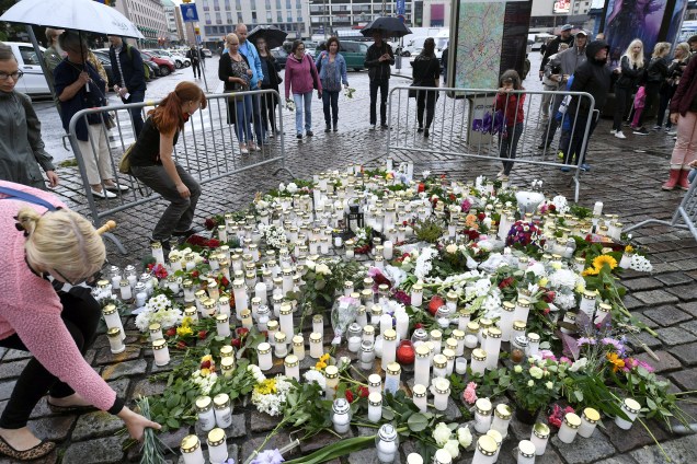 Pessoas levam velas e flores para um memorial improvisado em homenagem às vitimas esfaqueadas na Praça do Mercado, em Turku, na Finlândia