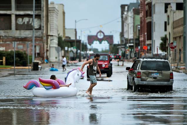 Pessoas caminham por uma rua inundada durante a passagem do furacão Harvey em Galveston, Texas - 27/08/2017