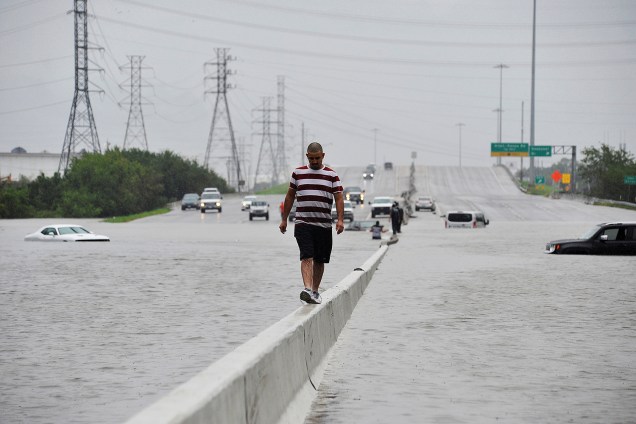 Pessoas caminham por uma rodovia inundada durante a passagem do furacão Harvey em Houston, Texas - 27/08/2017