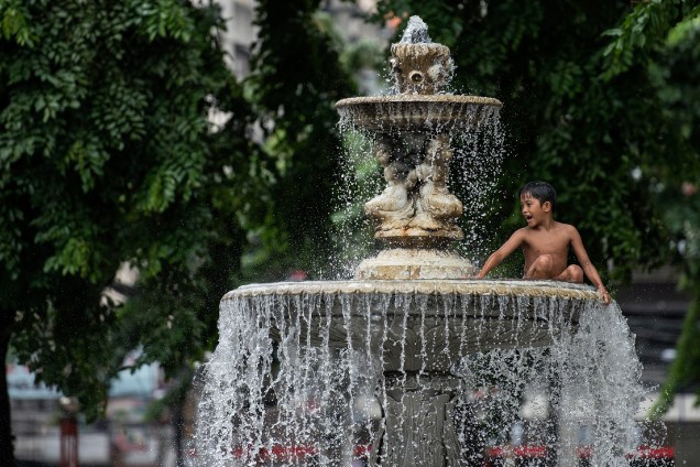 Garoto brinca em uma fonte de água publica na cidade de Manila, capital das Filipinas - 03/08/2017