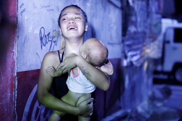 Mulher chora com seu bebê no colo após o marido ter sido morto em uma operação antidrogas na cidade de Caloocan, Metro Manila, nas Filipinas - 18/08/2017