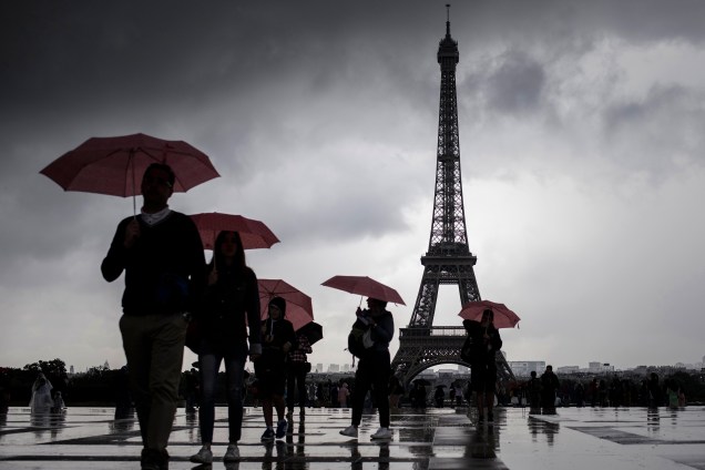 Pessoas andam com seus guardas-chuvas pelo pátio do Ancien Palais du Trocadéro, perto da Torre Eiffel, em Paris, na França - 10/08/2017