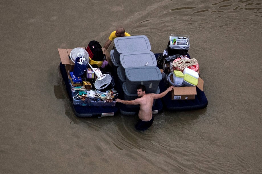 Moradores carregam seus pertences flutuando sobre a água da inundação trazida pela tempestade tropical Harvey, no nordeste de Houston, no Texas - 31/08/2017