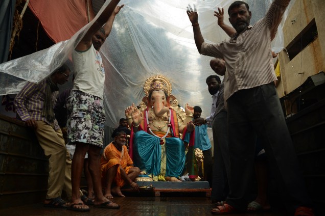 Devotos hindus transportam uma representação da divindade Ganesha coberta por plásticos, devido à chuva durante o início do Festival Ganesh Chaturthi. A tradição anual leva os indianos a imergir as divindades nas águas do mar da Arábia, em Mumbai - 25/08/2017