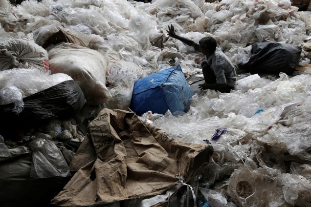 Homem trabalha separando folhas de polietileno e de plástico, em um pátio de reciclagem em Nova Deli, na Índia - 18/08/2017