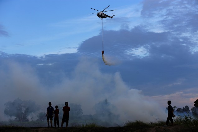 Um helicóptero pertencente ao Conselho Nacional para o Gerenciamento de Desastres da Indonesia despeja água para apagar o fogo em West Pemulutan, na Sumatra do Sul, Indonésia - 25/08/2017