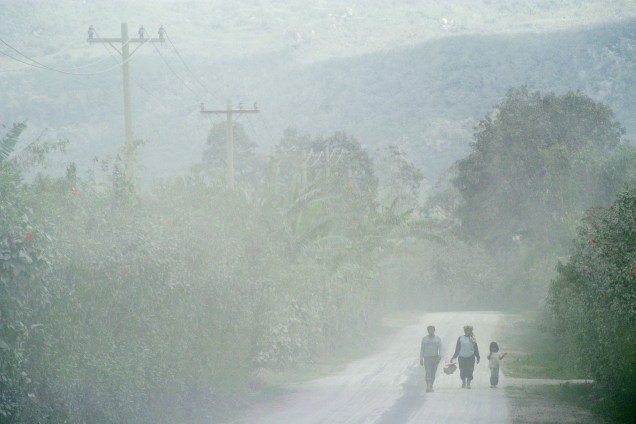 Pessoas caminham por uma estrada coberta de cinzas do vulcão Monte Sinabung, na vila de Naman Teran em Karo, província da Sumatra do Norte, na Indonésia - 03/08/2017