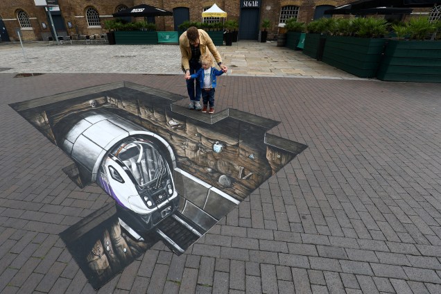 Um homem com uma criança observa de perto um desenho 3D feito perto do Museum of London Docklands, em Londres na Inglaterra - 03/08/2017 Um homem com uma criança observa de perto um desenho 3D feito perto do Museum of London Docklands, em Londres na Inglaterra - 03/08/2017