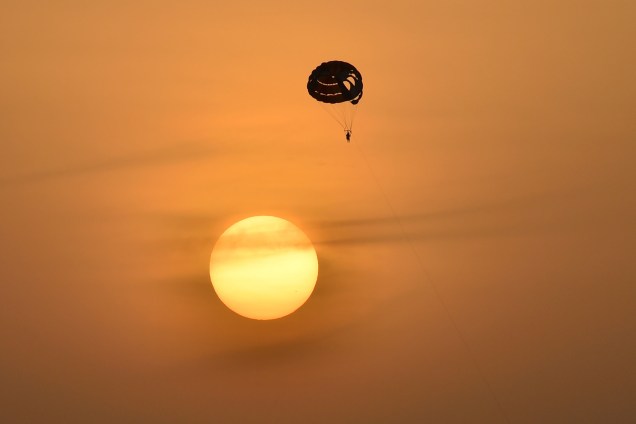 Uma pessoa navega pelo céu de Dubai, nos Emirados Árabes Unidos, em um paraquedas durante o pôr do sol  - 23/08/2017