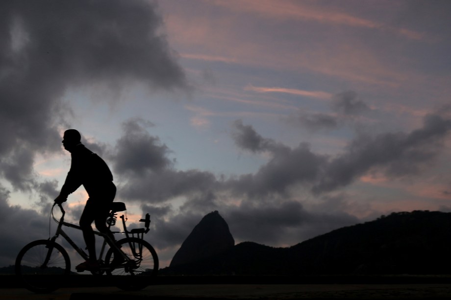Um homem é fotografado andando de bicicleta durante o pôr do sol no Rio de Janeiro, com a montanha do Pão de Açúcar ao fundo - 31/08/2017