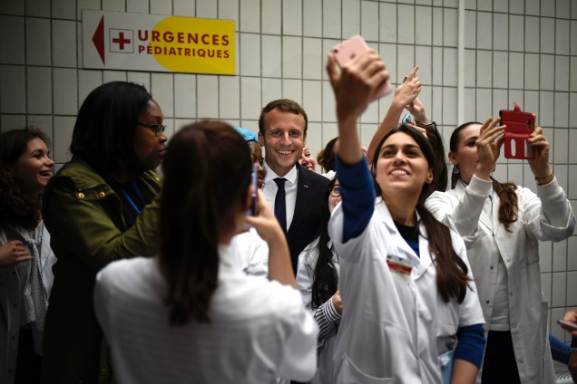 O presidente francês, Emmanuel Macron tira selfies com membros da equipe médica durante visita ao hospital pediátrico Robert Debre em Paris - 09/08/2017