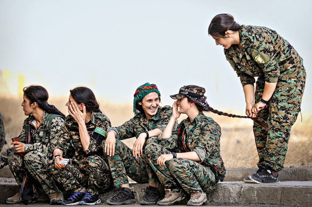 Syrian Democratic Forces (SDF) female fighters sit together on a curb in the city of Hasaka, northeastern Syria, August 9, 2017. REUTERS/Rodi Said TPX IMAGES OF THE DAY