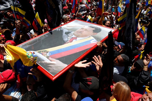 Partidários do ditador da Venezuela, Nicolás Maduro carregam um retrato de Hugo Chávez do lado de fora do Palácio Legislativo Federal durante a primeira sessão da Assembleia Nacional Constituinte, em Caracas - 04/08/2017
