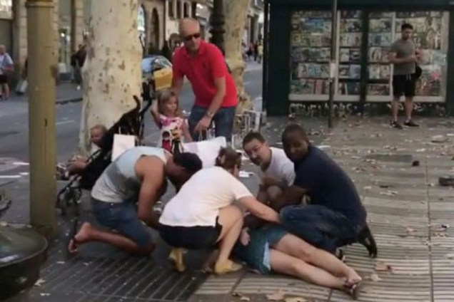 Pessoas ajudam uma mulher ferida depois de um atropelamento nos arredores da avenida Las Ramblas, no centro de Barcelona, na Espanha - 16/08/2017
