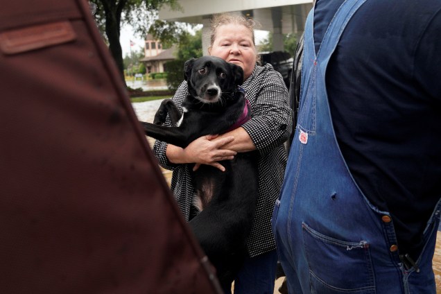 Mulher carrega seu cachorro para um caminhão militar durante evacuação de áreas inundadas após passagem do furacão Harvey em Dickinson, no estado americano do Texas - 27/08/2017